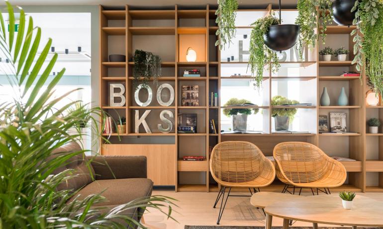 Salle de lecture moderne avec plantes et étagères à livres.