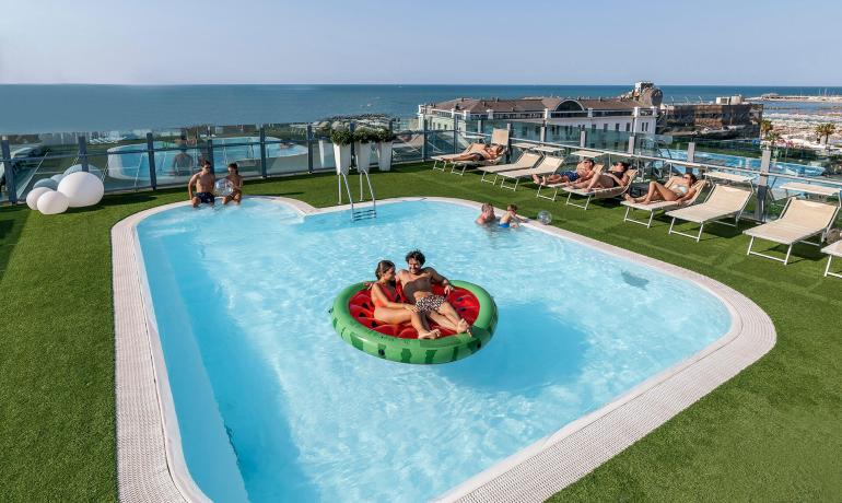 Piscina panoramica con vista mare e persone rilassate.