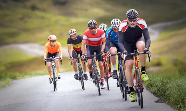 Gruppo di ciclisti su una strada di campagna in salita.