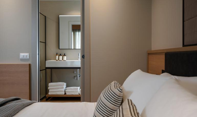 Camera moderna con bagno, letto e cuscini a righe.