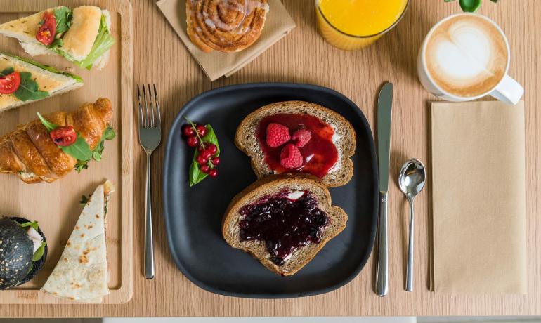 Colazione con pane e marmellata, croissant, succo e cappuccino.