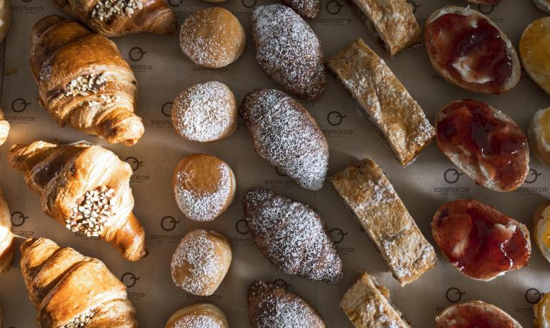 Assortimento di pasticceria con croissant e dolci vari.