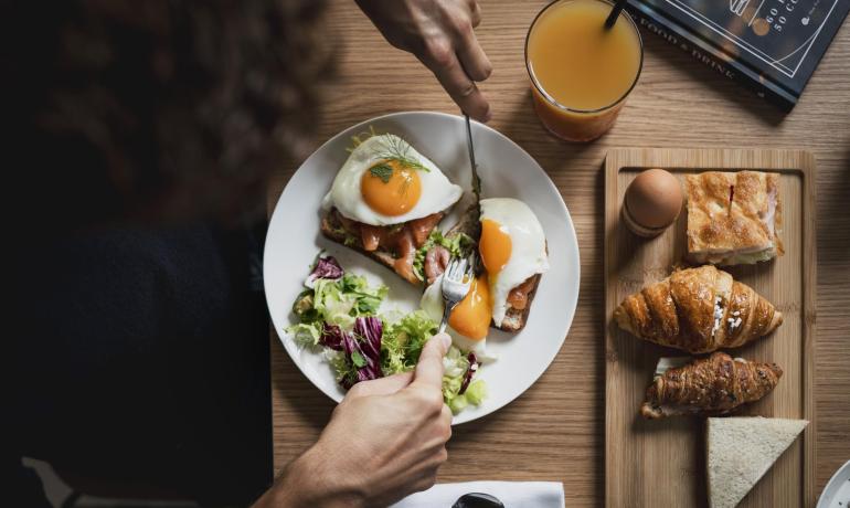 Colazione con uova, insalata, croissant e succo d'arancia.